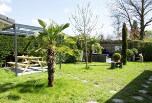 A garden with a picnic table, a palm tree, and a small tree.
