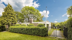 A residential property with a well-maintained lawn, a gated entrance, and a large tree in the background. - Holiday Home in Kortgene Near Lake Veere (Kortgene)
