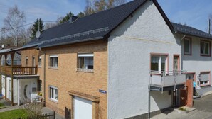 Una casa a due piani con facciata bianca e tetto scuro.