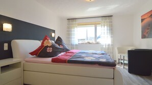 Una camera da letto con un letto, comodini, una finestra con tende, una scrivania e una sedia.