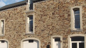 A stone building with three garage doors and two windows with shutters.