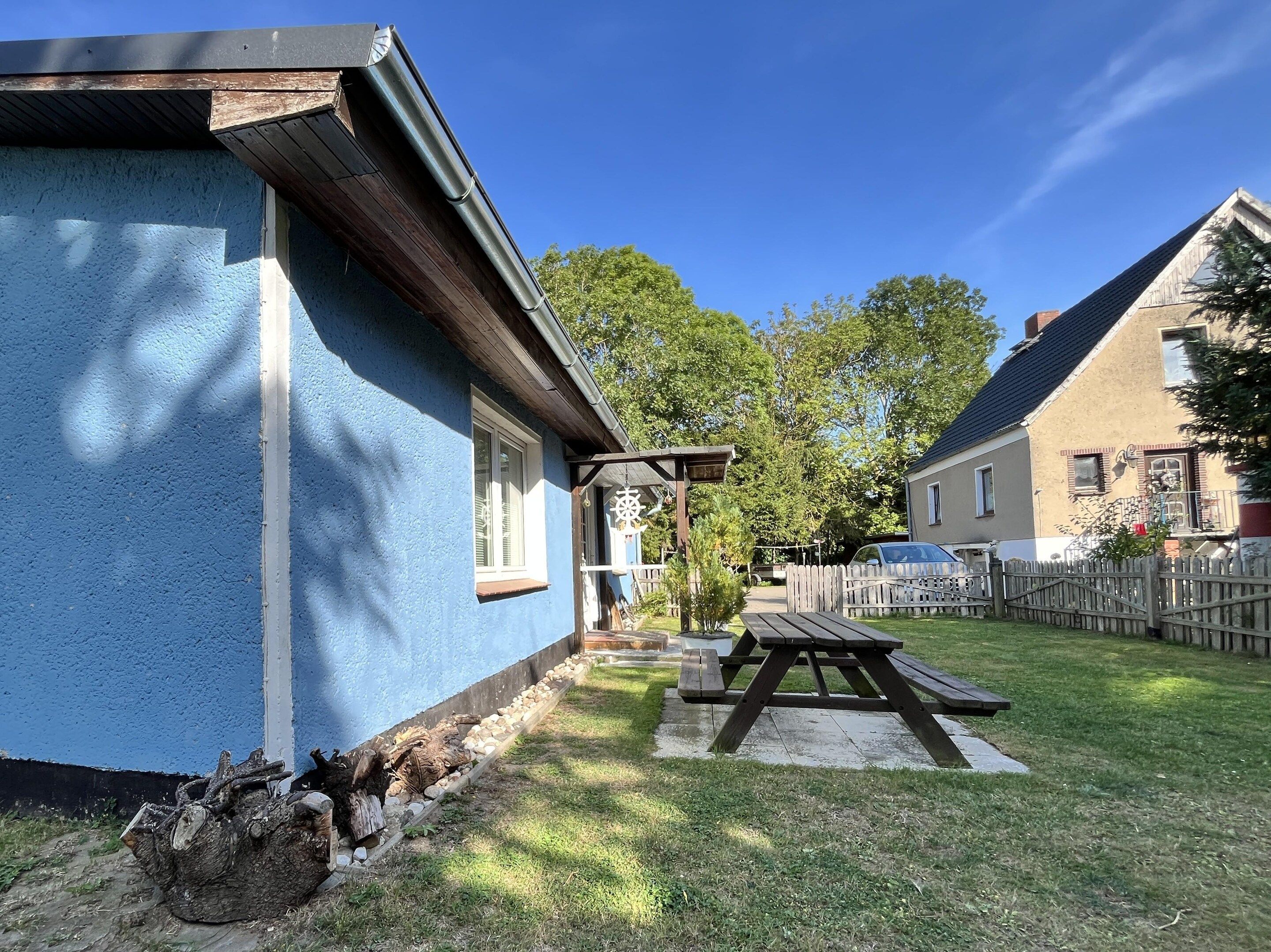 A residential property with a blue exterior, a wooden deck, and a picnic table.