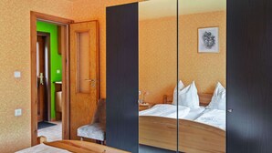 A hotel room with a bed, a chair, a wardrobe, and a mirror. - Quiet Home Near Vessertal (Schleusegrund)
