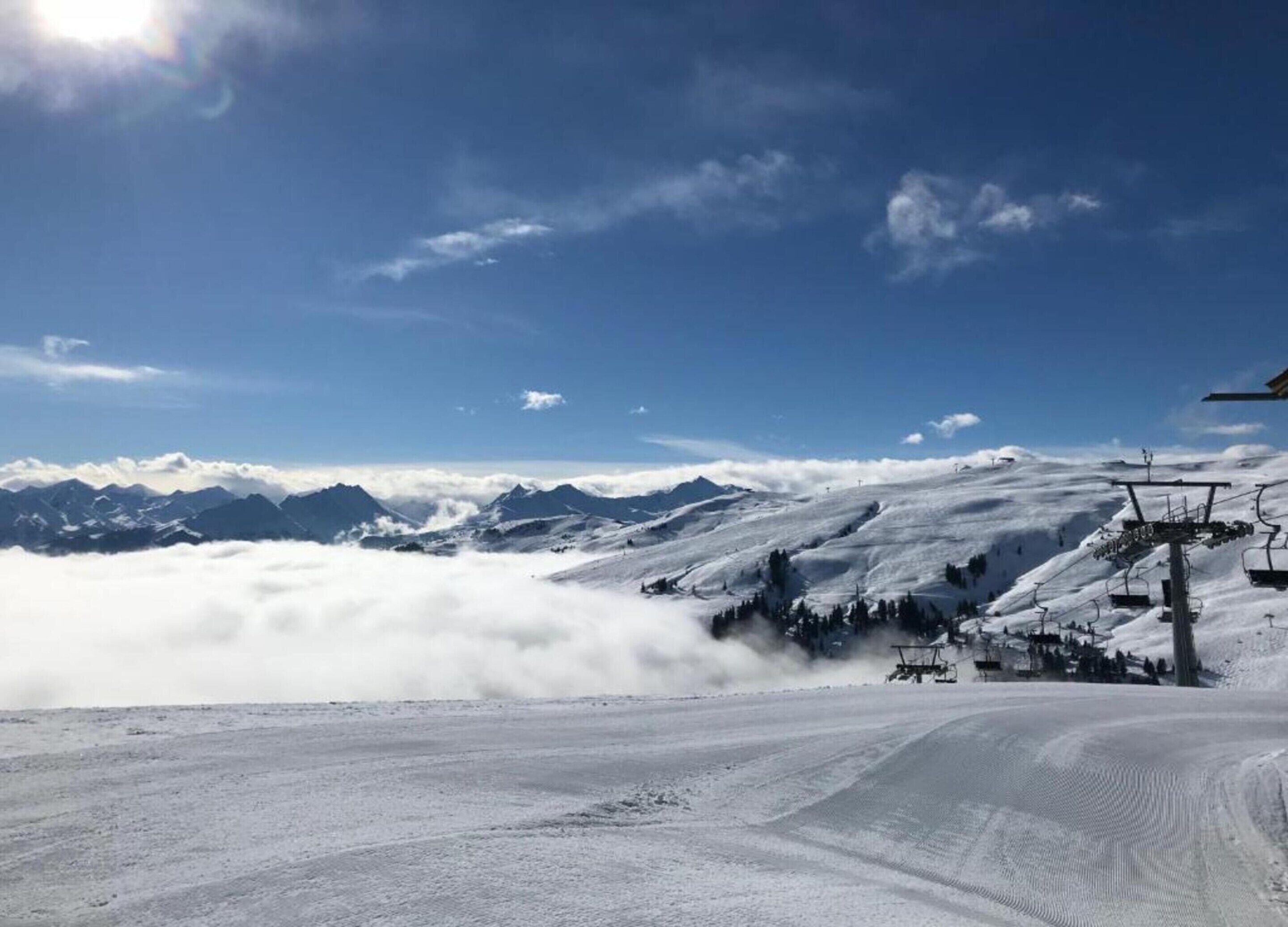 A snowy mountain landscape with a ski lift and a clear sky.