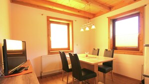 A dining area with a wooden table and chairs, a radiator, and a window with blinds. - Spacious Apartment in Mittersill near Ski Points (Mittersill)