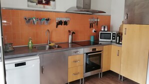 Eine moderne Küche mit orangefarbenen Fliesen, Edelstahlgeräten und Holzschränken.