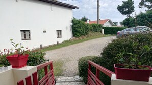 Ein Steinweg führt zu einem weißen Gebäude mit roten Geländern und Topfpflanzen.