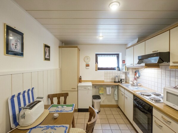 A compact kitchen with a dining area, featuring a toaster, a sink, a stove, and a microwave. - Wohnung in Bad Grund (Bad Grund)