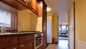 Una cucina con mobili in legno, forno a incasso e una finestra con persiane.
