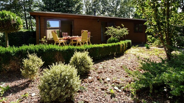 Una baita di legno con un patio attrezzato con tavolo e sedie.