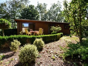 A wooden cabin with a patio area featuring a table and chairs. - Chalet in Garderen With Fenced Garden (Garderen)