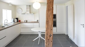 Een moderne keuken met witte kasten, een ronde tafel en een houten paal.