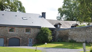 Een gebouw van steen met een grijs dak, een grindpad en een bordje waarop 'B&B' staat.