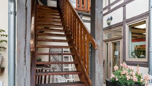 Una escalera de madera con barandilla metálica que conduce a la entrada de un edificio.