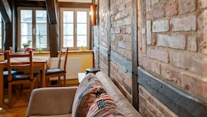 Una habitación acogedora con paredes de ladrillo visto, techo de madera y un sofá con un plaid estampado.