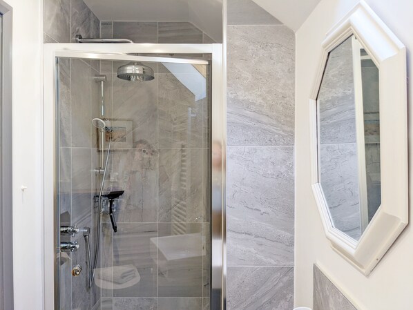 A modern shower enclosure with a glass door, a handheld showerhead, and a handheld shower attachment.