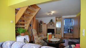 Uma sala de estar com escada, um sofá, uma mesa de centro e uma estante de livros.