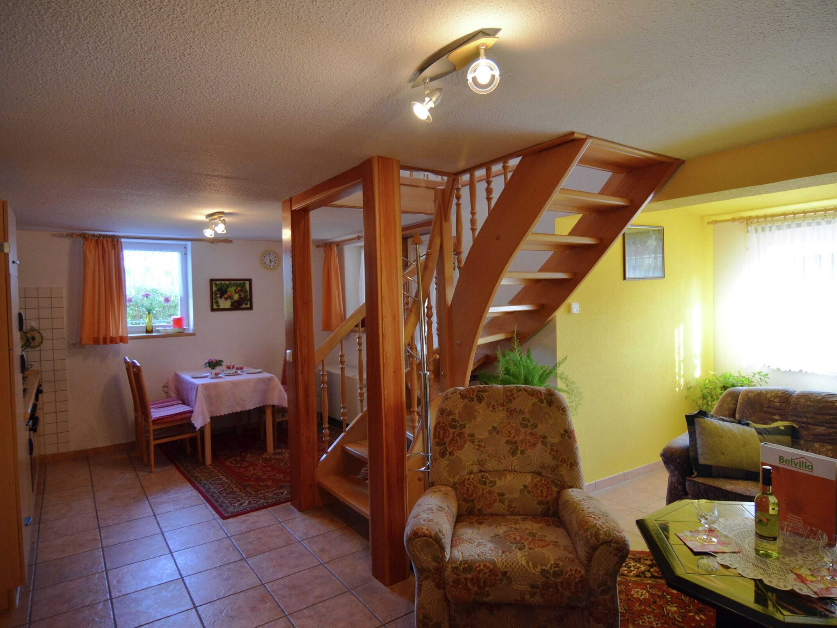 A living room with a wooden staircase, a dining area, and a sofa.