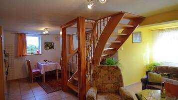 A living room with a wooden staircase, a dining area, and a sofa.