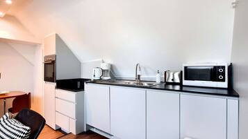 Kitchen area with oven, coffee maker, microwave, and sink.