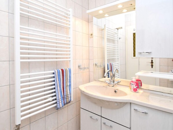 A modern bathroom with a white vanity, a large mirror, and a towel rack with a striped towel.