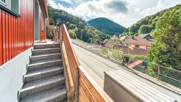 Una escalera que lleva a un balcón con vistas a un valle con casas y montañas.