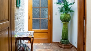 A hallway with a wooden door, a green plant, and a table with magazines. - A Small Studio of a Nature Stone House (Aywaille)