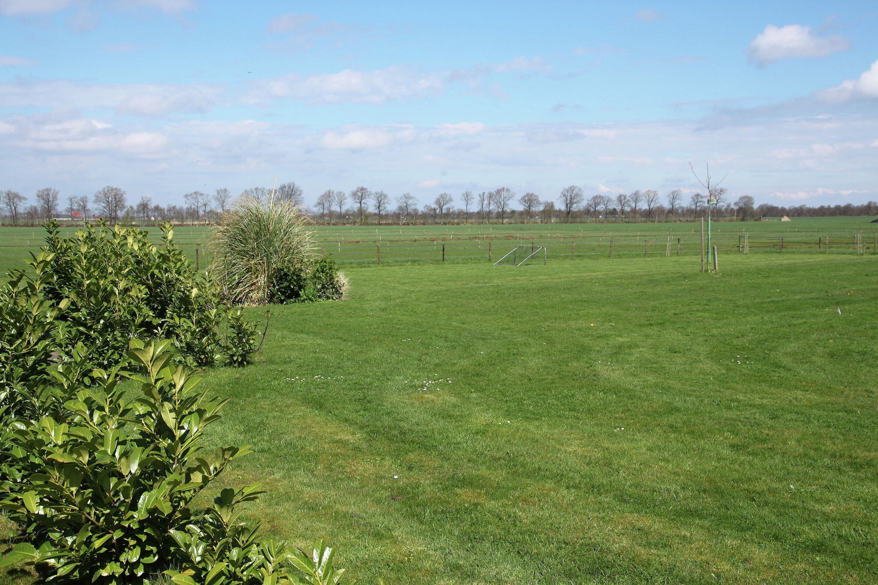 Un champ herbeux avec un poteau de but et une clôture.