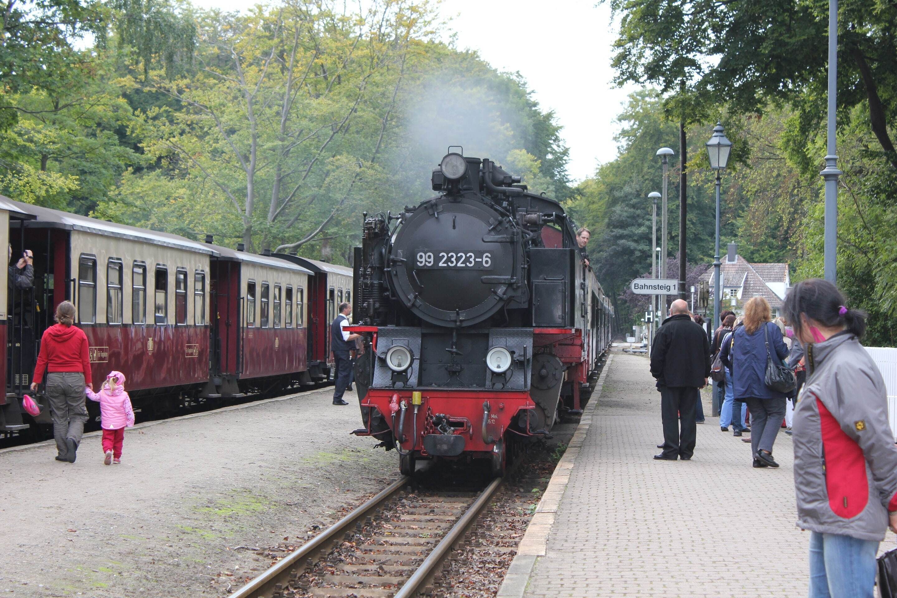 Perron van een treinstation met een stoomlocomotief met nummer 99 2323-6.