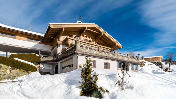 A chalet-style building with a wooden facade, a balcony, and a snow-covered landscape. - Comfy Apartment in Hollersbach im Pinzgau near Lake (Hollersbach im Pinzgau)