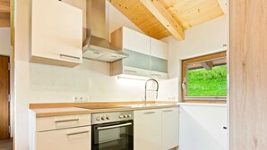 A modern kitchen with white cabinetry, a built-in oven, and a window with a view of greenery. - Comfy Apartment in Hollersbach im Pinzgau near Lake (Hollersbach im Pinzgau)