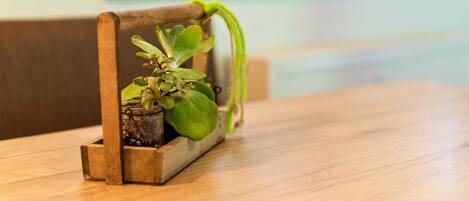 Un support à plantes en bois avec une plante en pot posée sur une table en bois.