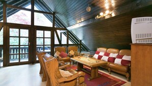 A cozy room with wooden furniture, a large window, and a view of the outdoors. - Apartment in a Former Farmhouse (Mastershausen)