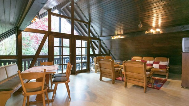 A spacious room with a high ceiling and large windows, wooden furniture, and a fireplace. - Apartment in a Former Farmhouse (Mastershausen)