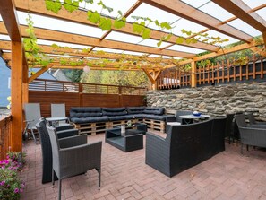 Eine Terrasse im Freien mit einer Holz-Pergola, einer Steinmauer und einem Sitzbereich.