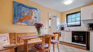 A cozy kitchen with a wooden table and chairs, a map on the wall, and a window with a view. - Stylish Apartment in Merschbach near Forest (Merschbach)
