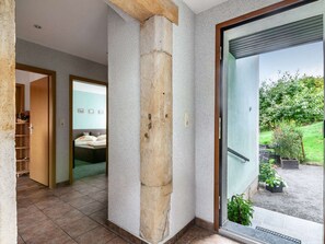 A modern interior with a stone pillar, a bathroom with a bathtub, and a view of a garden through a glass door. - Idyllische Ferienwohnung in Lichtenhain (Sebnitz)