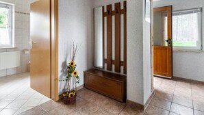 Een gang met een houten bankje, een spiegel aan de muur en een deur naar een badkamer.