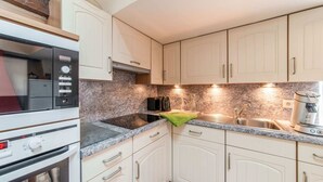 A kitchen with white cabinets, a built-in oven, a microwave, a sink, and a coffee maker. - Characteristic Holiday Home With Balcony (Gouvy)