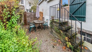 A rustic outdoor seating area with a table and chairs, surrounded by greenery and a wooden fence. - Characteristic Holiday Home With Balcony (Gouvy)