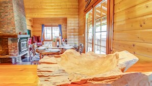 Eine Blockhütte mit Essbereich, Kamin und großen Fenstern.