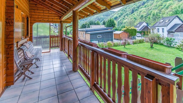 Ein Holzbalkon mit Fliesenboden, Holzgeländern und einer Bank.