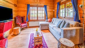 Ein gemütliches Blockhaus-Interieur mit Fernseher, Ledersessel, Sofa und Couchtisch.