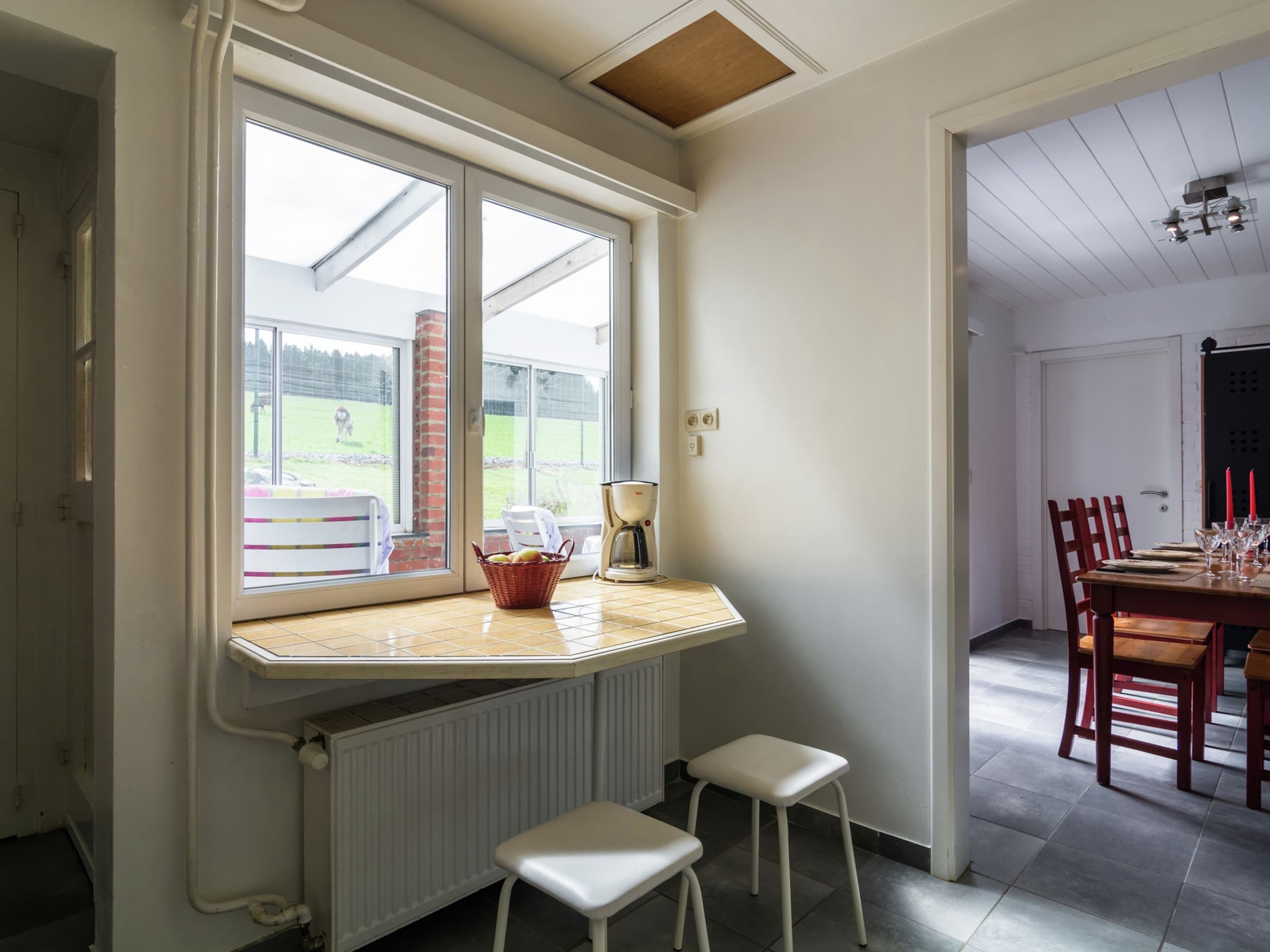 A kitchen with a bay window, a coffee maker, a basket, and a radiator.
