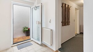 A modern hallway with a glass door leading to a balcony, a radiator, and a wall-mounted towel rack. - Cozy Apartment in Wismar near Baltic Sea (Wismar)