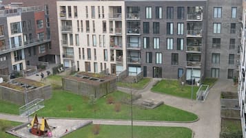 Un edificio residencial de varios pisos con balcones, un área de juegos y una estructura de techo verde.