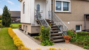 A two-story house with a front porch, a staircase, and a well-maintained garden.