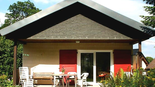 A small house with a covered patio, a dining table, and chairs. - Charming Holiday Home in Liebenscheid by Forest (Liebenscheid)