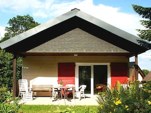 A small house with a covered patio, a dining table, and chairs. - Charming Holiday Home in Liebenscheid by Forest (Liebenscheid)