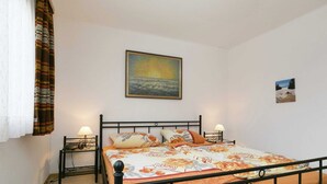 A bedroom with a bed, two bedside tables, a wall-mounted painting, and a window with curtains. - Charming Holiday Home in Liebenscheid by Forest (Liebenscheid)